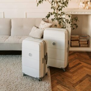 Two packed cream color suitcases in the serene living room with hardwood floors and oatmeal color sofa and area rug